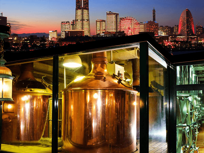 a night photograph of yokohama brewery with the yokohama skyline in the background