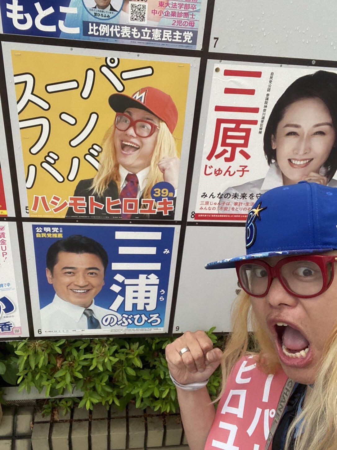 Super Humbaba standing next to one of his election posters